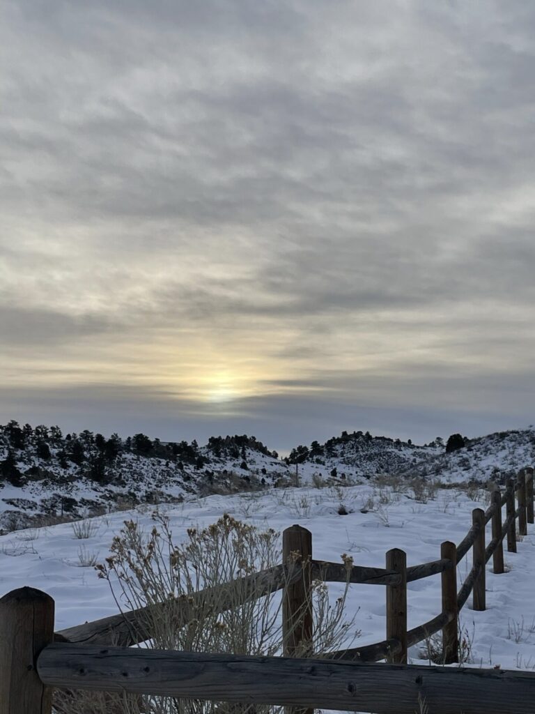 Fence across a snowy field at sunrise